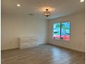 Bright bedroom with wood-look tile flooring, modern light fixture, and a window view at 4300 Avanti Cir, North Port, FL 34287