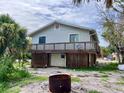 Home exterior on stilts with a wooden deck and a glimpse of the surrounding nature at 8416 Little Gasparilla Is, Placida, FL 33946