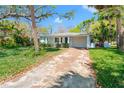 Inviting single-story home with a well-maintained front lawn, mature trees, and a long driveway leading to the garage at 8285 28Th N Ave, St Petersburg, FL 33710