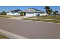 Exterior view of home with solar panels, two car garage and tropical landscaping in a sunny neighborhood at 1405 Blossom Bayou Cir, Ruskin, FL 33570