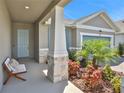 Inviting front porch with light teal door, stone pillars, and landscaping at 7465 Sea Manatee St, Parrish, FL 34219