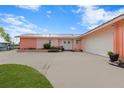 Pink mid-century modern home with attached garage, mature landscaping, and spacious driveway at 351 Harbor Psge, Clearwater Beach, FL 33767