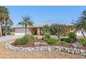 Inviting single-story home showcases lush landscaping with gravel, rock border, and mature palm trees at 909 Dawn St, Venice, FL 34285