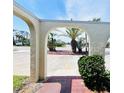 Home entryway with unique archway framing tropical plants and a street view in a sunny landscape at 933 Harbor S Dr, Venice, FL 34285