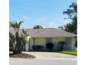 Home exterior featuring a private driveway with lush landscaping, bushes, and a well manicured lawn at 933 Harbor S Dr, Venice, FL 34285