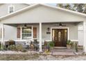 Charming covered front porch with seating, fans, and a beautiful wooden double door entrance to the home at 7157 Knoxville Dr, Webster, FL 33597