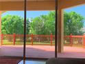 Inviting back porch with a stained wood deck and railings overlooks the lush green backyard and mature trees at 5271 Visionary Ct, Sarasota, FL 34233