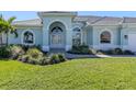 Inviting home featuring arched windows, a bright green lawn, and lush landscaping enhances its curb appeal at 519 Purslane Pt, Venice, FL 34293