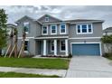 Gray two-story home with a one-car garage, palm trees, blue shutters, and white trim at 9572 Brave Buck Ave, Land O Lakes, FL 34638
