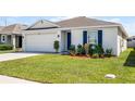 Attractive single-story home showcasing vibrant landscaping, a two-car garage, and a beautiful blue front door at 38370 Sonnet Landing Ave, Zephyrhills, FL 33540