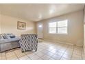 Bright living room showcasing tile floors, a comfortable sofa, chair, and ample natural light from the large window at 5330 Dr Martin Luther King Jr St S, St Petersburg, FL 33705