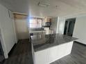 An incomplete kitchen with grey granite island and countertops, white cabinets, and stainless steel microwave at 10228 Amadeus Dr, Port Richey, FL 34668