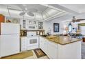 Bright kitchen with white cabinets, granite countertops, and modern appliances open to living room at 12300 Vonn Rd # 1102, Largo, FL 33774