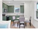 Eat in kitchen with olive green cabinets, stainless steel appliances, and stylish tile backsplash at 9608 Brave Buck Ave, Land O Lakes, FL 34638
