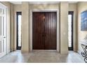 Spacious entryway with a decorative wood double door, sidelights, and tile flooring at 7020 Hawks Harbor Cir, Bradenton, FL 34207