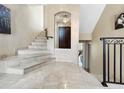 Elegant foyer featuring marble flooring, staircase with iron railing, and a view of the front door at 7020 Hawks Harbor Cir, Bradenton, FL 34207