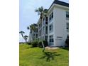 Exterior shot of a well-maintained multi-story condo building enhanced by mature palm trees on a sunny day at 4310 Falmouth Dr # 301, Longboat Key, FL 34228