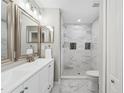 Elegant bathroom with double vanity, modern fixtures, and a tiled walk-in shower with decorative inlays at 12534 Chenwood Ave, Hudson, FL 34669