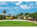 Bright yellow house with blue shutters, well-manicured lawn, and a circular driveway leading to the home at 401 Sunset Dr, Venice, FL 34285