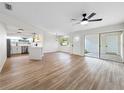 Bright open-concept living room with wood flooring, ceiling fan, and sliding glass doors leading to outdoor at 5136 Cedar Hammock Dr, Sarasota, FL 34232