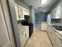 Eat-in kitchen with white cabinets, stone countertops, black appliances, and tile flooring at 7169 Holiday Dr, Spring Hill, FL 34606