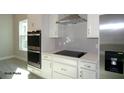 Modern kitchen featuring stainless steel appliances, white cabinetry, and a sleek cooktop at 9544 Brave Buck Ave, Land O Lakes, FL 34638