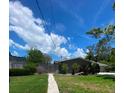 A fenced-in backyard with a path leading to a house, surrounded by trees and greenery under a bright sky at 4571 Clearwater Harbor S Dr, Largo, FL 33770