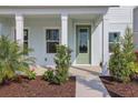Inviting front porch with white columns and a modern green front door, surrounded by landscaping at 130 Bragg Ln, Lakewood Ranch, FL 34240