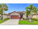 Inviting single-story home with a two-car garage, manicured lawn, and tropical landscaping at 4808 111Th E Ter, Parrish, FL 34219