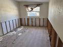 An empty bedroom with damaged drywall, exposed framing, and a window with a view of the outdoors at 9015 Bay Ne St, St Petersburg, FL 33702