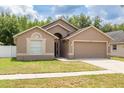 Exterior shot of a tan single-story home with a two-car garage and well-manicured front lawn at 18941 Twinberry Dr, Tampa, FL 33647