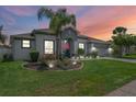 Charming single-story home with a manicured lawn, lush landscaping, and a vibrant blue front door at dusk at 13365 Chesapeake Pl, Spring Hill, FL 34609