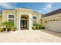 Inviting home entrance with well-manicured landscaping, brick driveway, and double-door entryway at 14041 Bassingthorpe Dr, Spring Hill, FL 34609