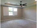 Bright bedroom features a ceiling fan, neutral carpeting, and a window with plantation shutters at 13639 Salinas St, Venice, FL 34293