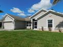 Well-maintained single-story home with lush lawn, mature trees, and a driveway leading to an attached two-car garage at 401 Malpelo Ave, Punta Gorda, FL 33983