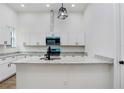 Bright kitchen with white cabinets, speckled granite countertops, stainless steel appliances, a black faucet and modern lighting at 14 S Forest St, Plant City, FL 33563