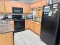 Kitchen featuring black appliances, granite-look counters, light wood cabinets, and tiled floor at 3433 Dragon View Ct, Valrico, FL 33594