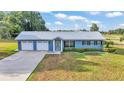 Ranch-style home with metal roof, two-car garage, and landscaped yard at 6110 Downing St, Dover, FL 33527