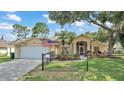 Tan one-story house with a white garage door, screened porch, and fenced yard at 23338 Duchess Ave, Port Charlotte, FL 33954