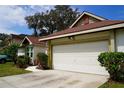 Front view of a one-story house with a white garage door and landscaping at 7801 Glascow Dr, New Port Richey, FL 34653