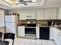 Bright kitchen features white cabinets, stainless steel appliances, and tile flooring at 11231 Dollar Lake Dr # 1, Port Richey, FL 34668