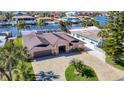 Beautiful aerial view of a waterfront home with a paved driveway, lush landscaping, and neighborhood access to the water at 5509 Pilots Pl, New Port Richey, FL 34652