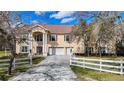 Charming two-story home with three-car garage, manicured front lawn, white fence and landscaping at 11175 Hyde St, Weeki Wachee, FL 34614