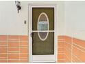 Up close front door with storm door and brick accents at 4745 Floramar Ter, New Port Richey, FL 34652