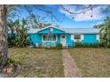 Charming blue cottage-style home with white trim, an American flag and a brick walkway to the front door at 1000 Michigan Blvd, Dunedin, FL 34698