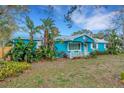 Charming blue cottage-style home with lush landscaping and a brick walkway leading up to the house at 1000 Michigan Blvd, Dunedin, FL 34698
