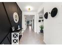 Stylish entryway featuring modern black accent wall, tiled floors, and an open view to the living area at 8538 Greenway Ave, Wesley Chapel, FL 33544