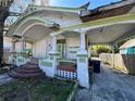 Single-story home showing the front porch, covered parking, and overgrown yard at 921 E 12Th Ave, Tampa, FL 33605