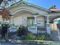 Single-story home featuring a covered porch, boarded windows, and gated yard at 921 E 12Th Ave, Tampa, FL 33605