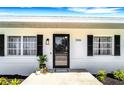 Welcoming entryway with a modern black glass front door, decorative shutters, and lush landscaping at 1046 Lee St, Englewood, FL 34224